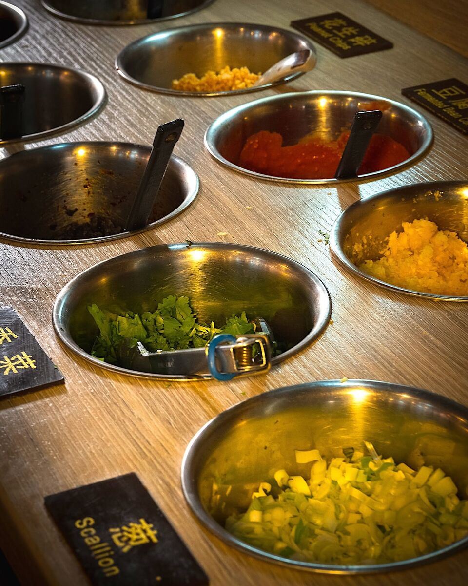 The self-serve sauce bar: steel bowls, each with a label such as Scallion and Peanut Chips