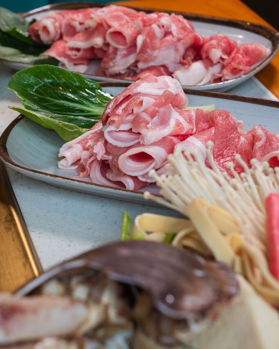 Stoneware plates of rolled lamb and pork with bok choy and enoki