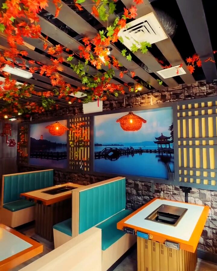 The dining room: autumn-leaf garlands overhead, teal booths and the lake mural
